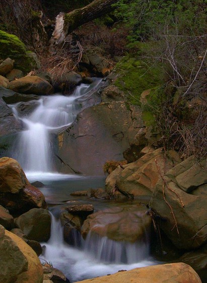 Mix Canyon Creek

This is an image of a creek up in Mix Canyon up in the hills that border Vacaville on the west.
This seasonal waterfall flows fairly strong in the winter and spring. It tapers off as the summer sets in and the rains stop.
At the top of the image there is a broken oak tree with a large limb reaching over the creek. The water flows down below the oak and over several large rocks and into a couple of small pools. 
The land on both sides of the creek is very rugged with large rocks and boulders mixed in with some trees and bushes struggling to hang on to the steep landscape. I used a slow shutter on this image to give the water a nice silky look.