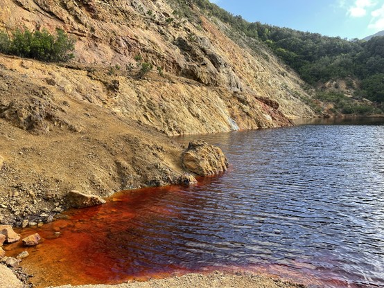 Different perspective: bright red lake surrounded by ochre-colored hills