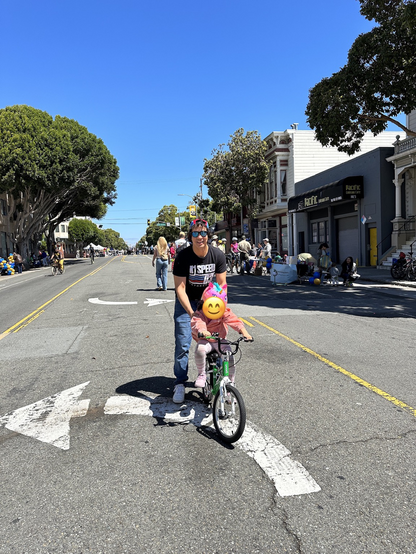 A father helps his child ride a bike on a street closed to cars