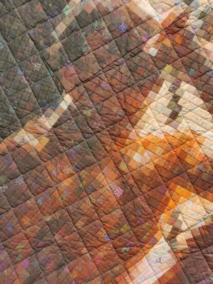 A close up of a very detailed, almost photorealistic quilt depicting a person.