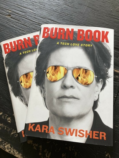 Black and white image of a person with aviator sunglasses on that have colored flames reflected in them