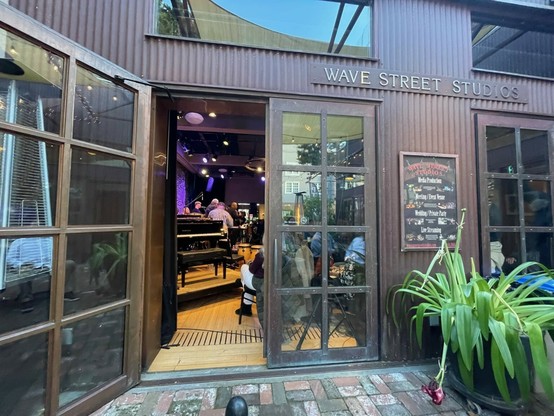 Performance stage of Wave Street Studios as viewed from their outdoor patio, through a stage-side glass door. Doors are often open, weather permitting. 
