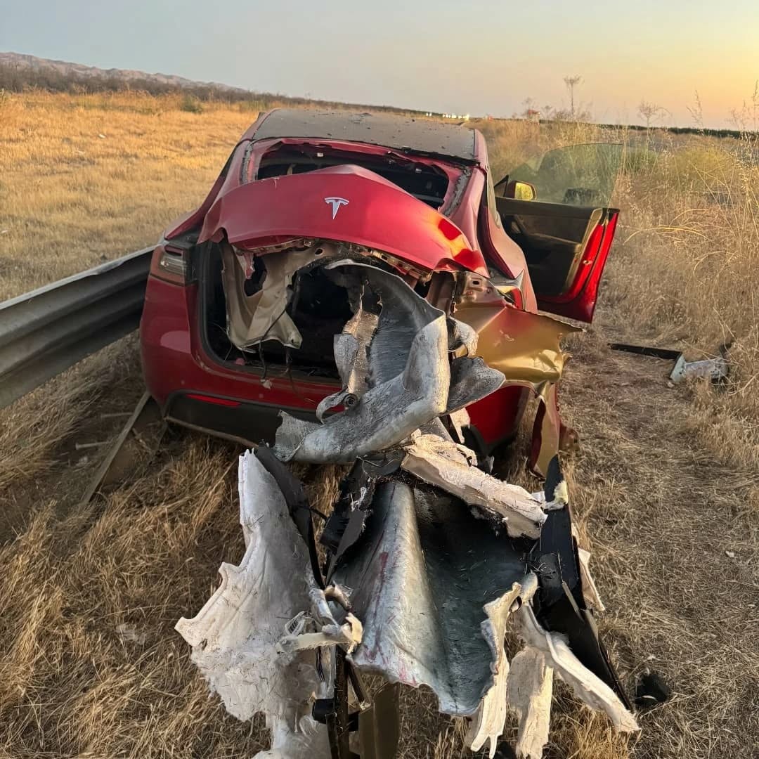 The railing exiting the rear of a red car. Both are shredded.