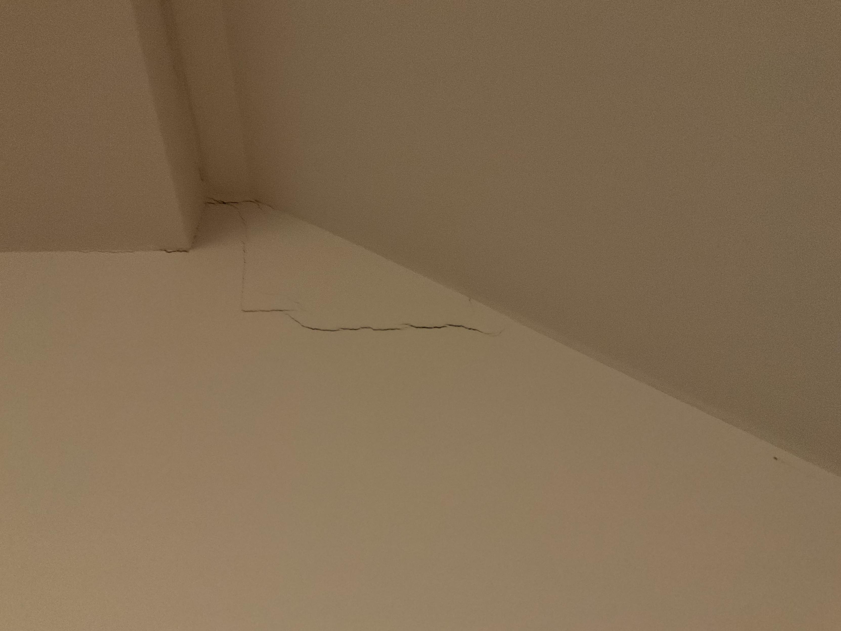 An L-shaped crack, approx 6 in by 12 in, in the crook under a staircase