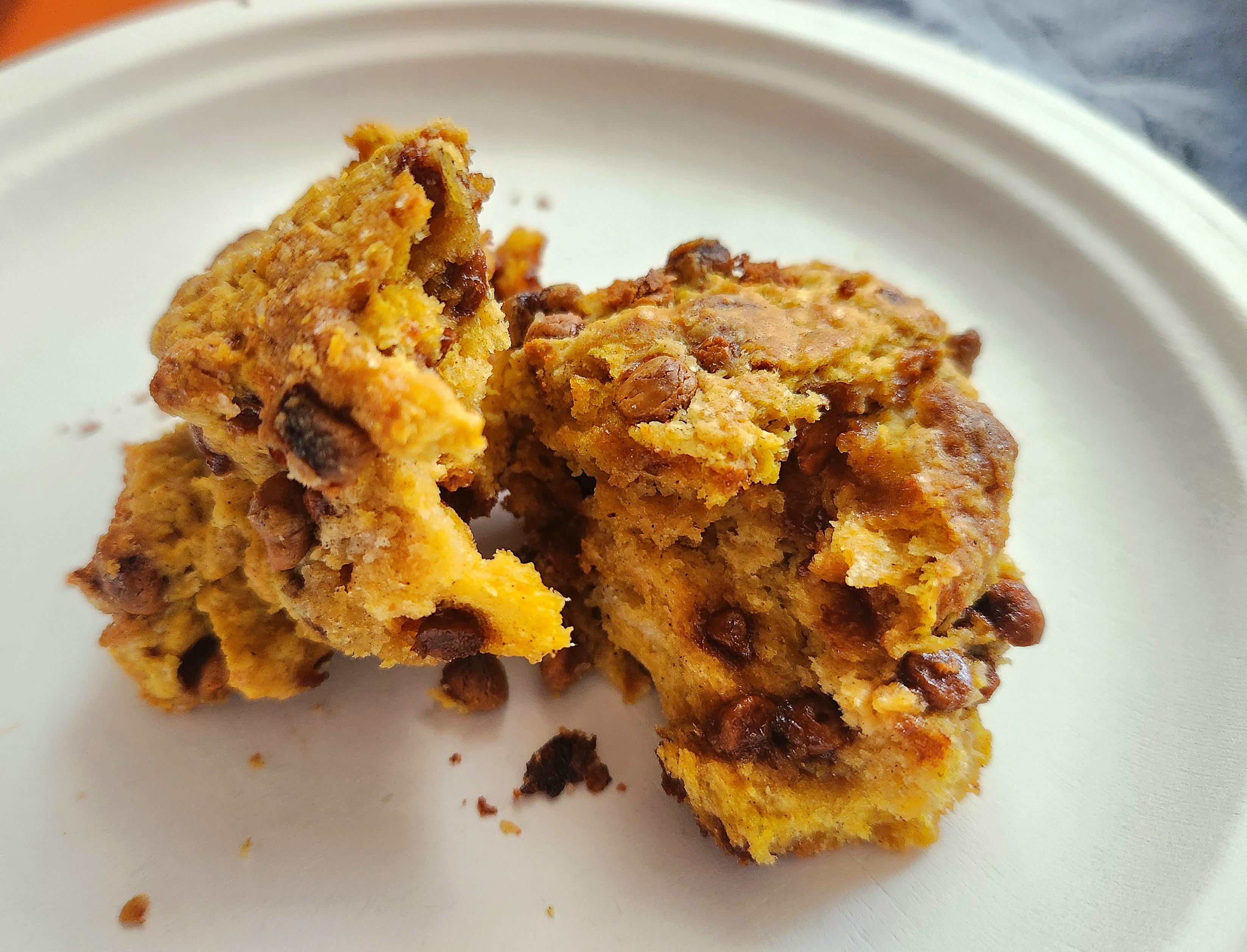A warm scones broken in half on a white paper plate.